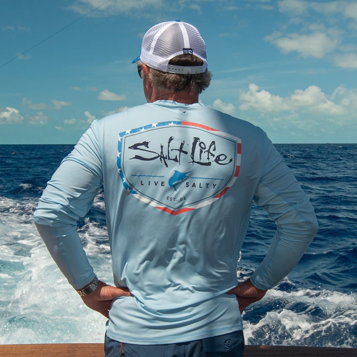 Man on a boat wearing Salt Life Stand Up LS SLX Mens Tee SLM6215 Airy Blue 
