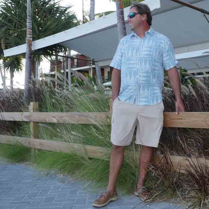 Skipper Gentry relaxing wearing our Optic Tails Woven Performance Fishing Shirt coastal blue front